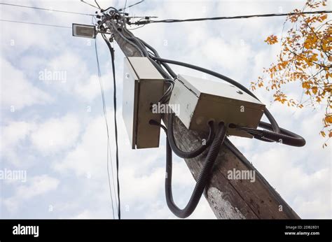 electrical pole with box on side and wire hanging down|street lights attached to pole.